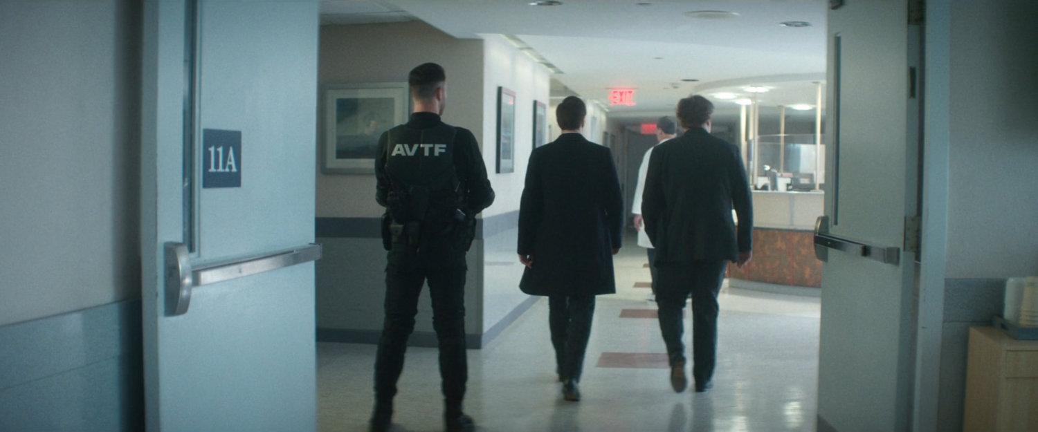 Daniel, Buck, and an AVTF Officer in the hallway of Metro-General.