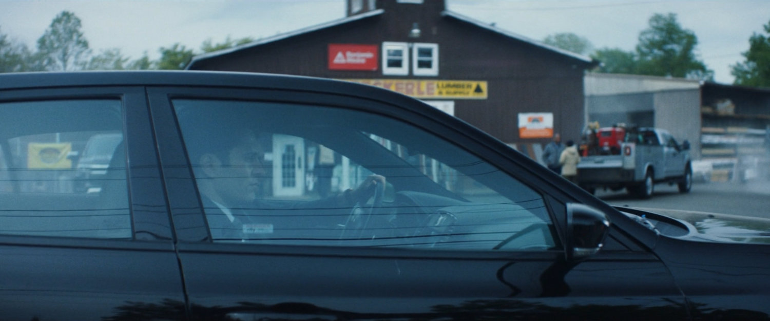 Daniel's car pulling into a lumber store parking lot.