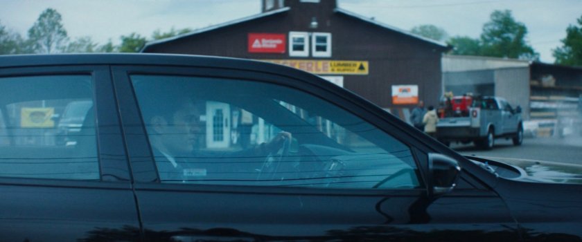 Daniel's car pulling into a lumber store parking lot.
