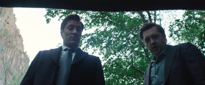 Buck and Daniel looking at a dead body in the trunk of a car.