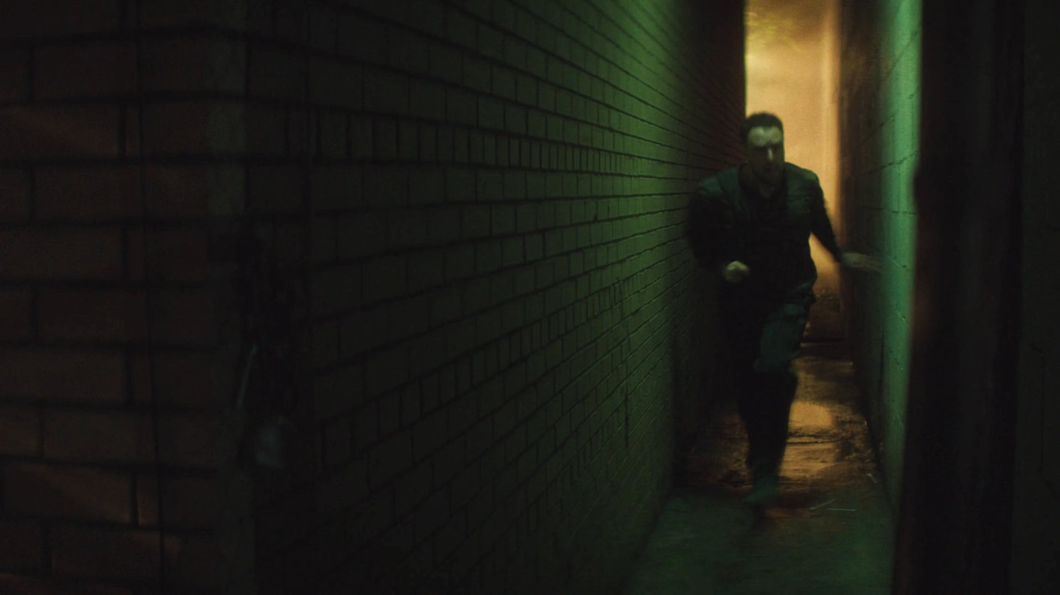 Flashback of Lionel running through an alley outside his apartment building.