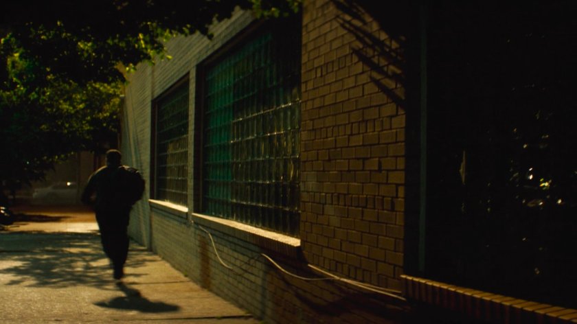 Flashback of Lionel running on the sidewalk outside his apartment building.