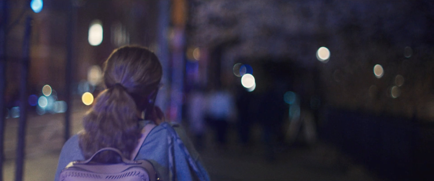 Interstitial: Woman walking along sidewalk at night.