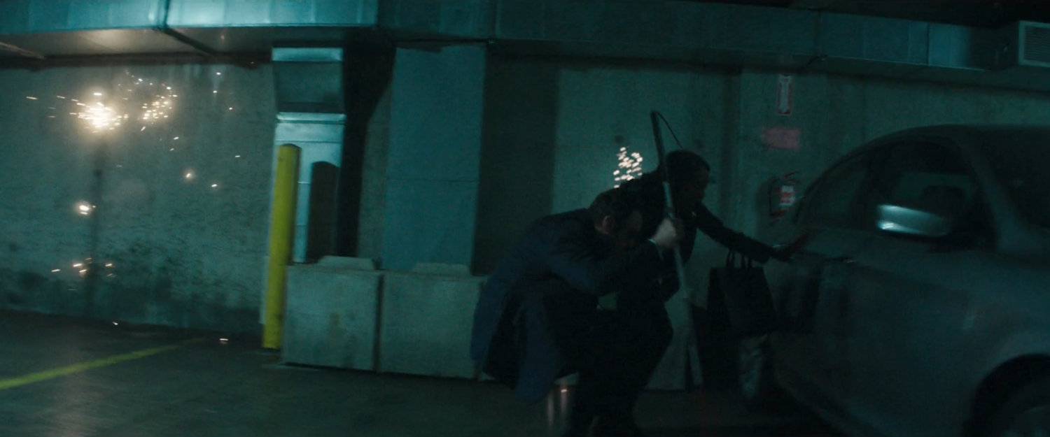 Matt and Kirsten hide behind a car in the underground parking level at the City Courthouse.