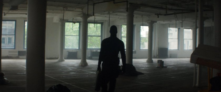 A man walking through an empty office in a building across the street from the city courthouse.