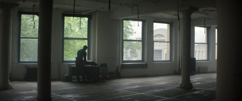 A man setting up a sniper rifle in a building across the street from the city courthouse.