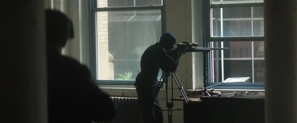 A sniper takes aim in a building across the street from the city courthouse.