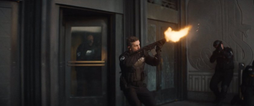 Powell fires his machine gun outside the city courthouse.
