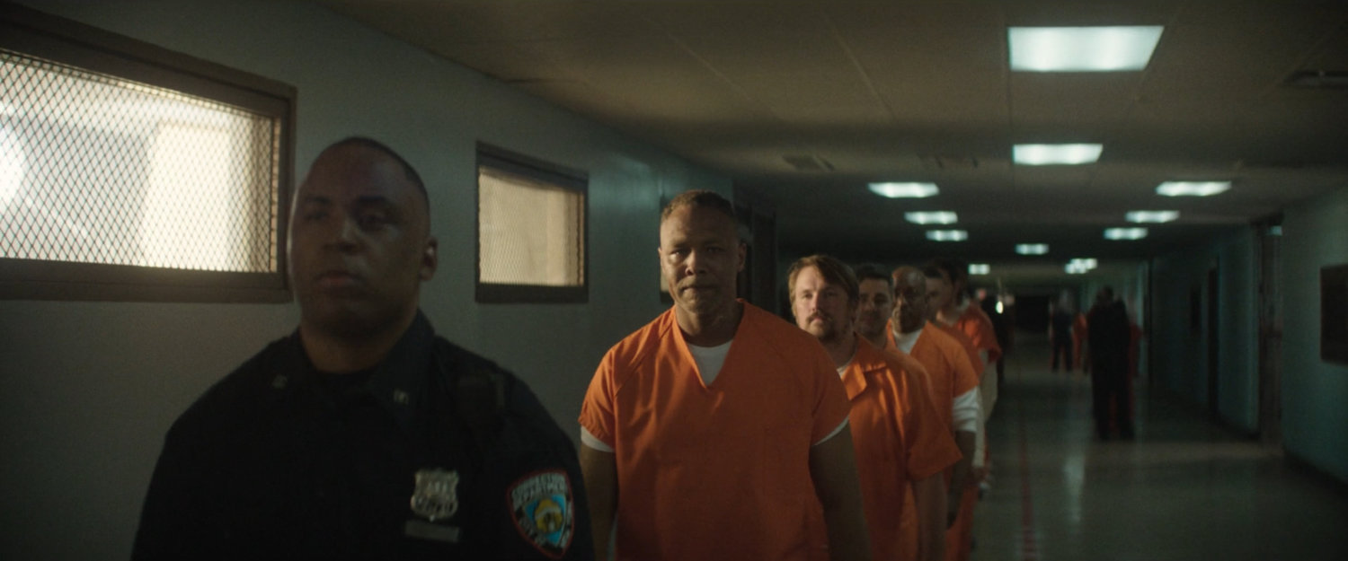 AVTF officers in orange jumpsuits walking along a hallway in Ryker's Penitentiary.
