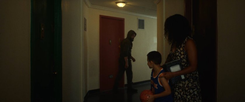 Frank leaving his apartment, walking past Isaiah and his mom.