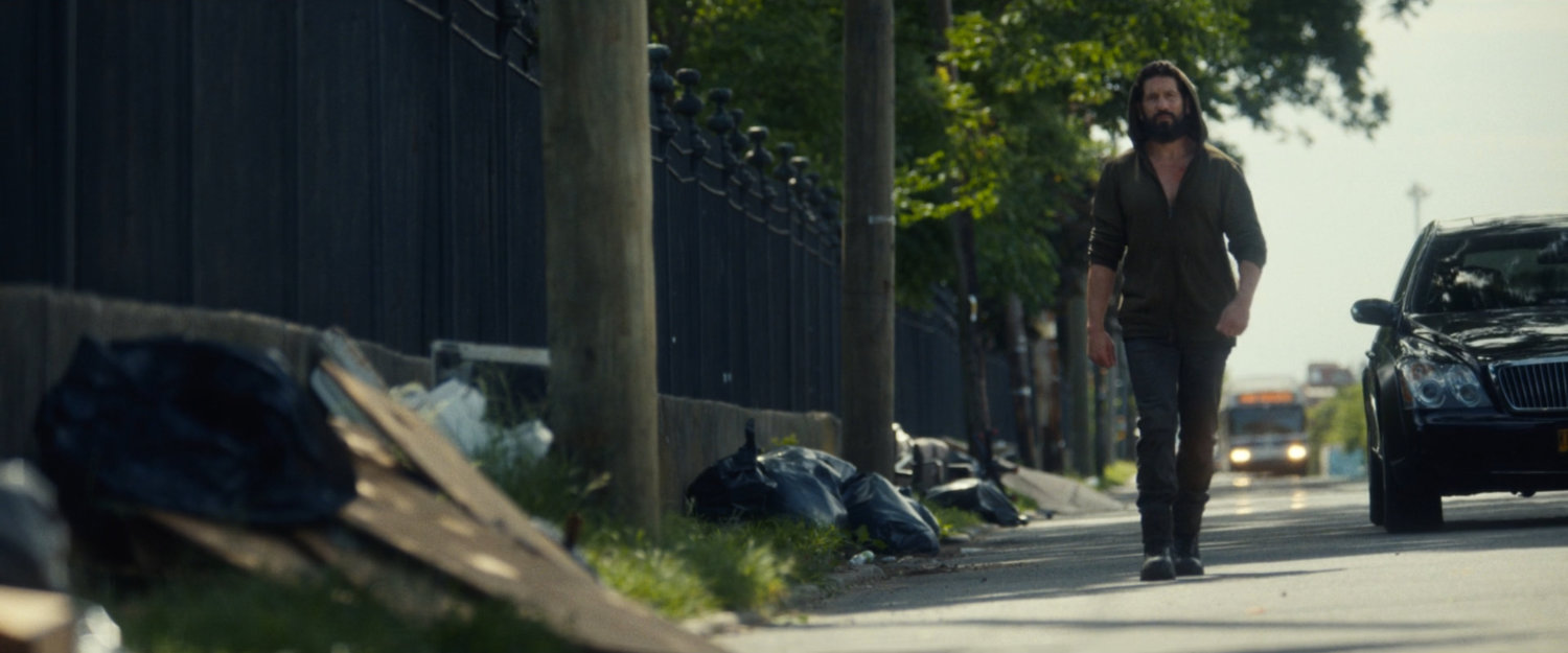 Frank walks along a road outside a cemetery.