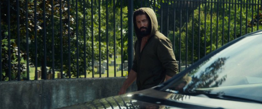 A car passes Frank as he walks along a road outside a cemetery.