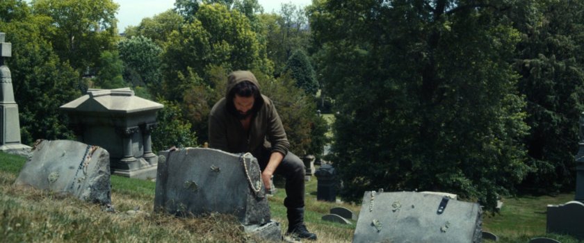 Frank kneels by the gravestones of his family at a cemetery.