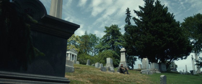 Frank sits by the gravestones of his family at a cemetery.