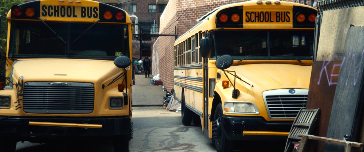A pair of school buses parked outside Frank's apartment building.