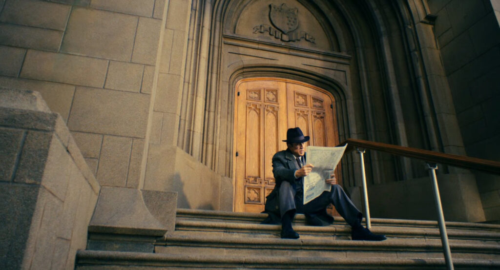 Ben reading a newspaper on the steps of a church.