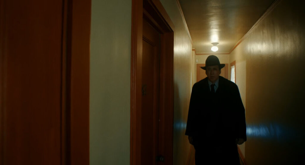 Ben walking along a hallway in his old apartment building.