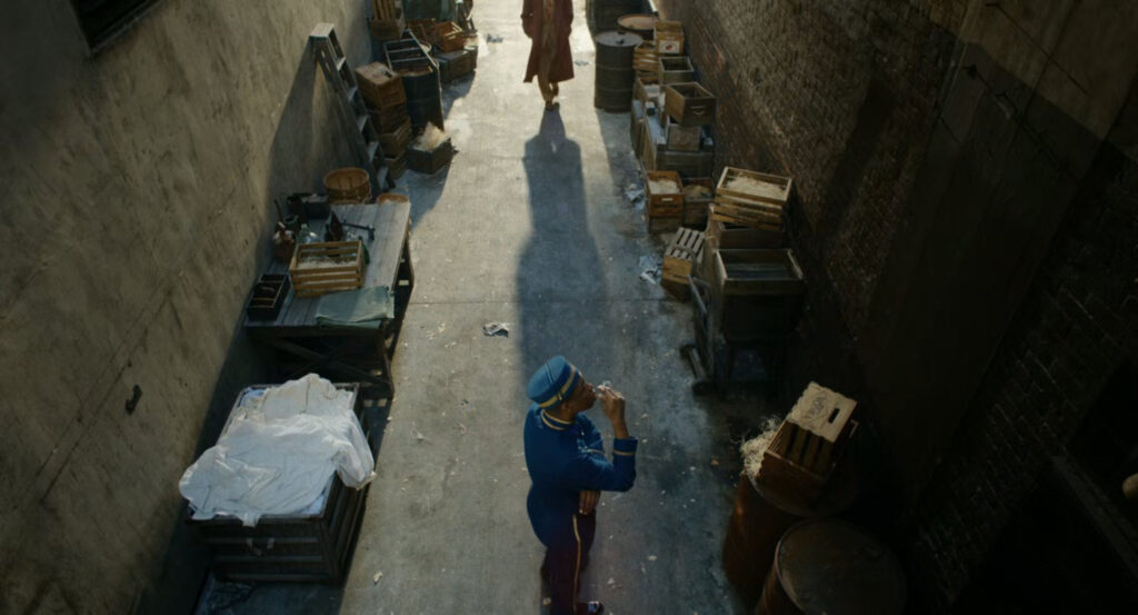 Robbie approaching a black bellhop in an alley behind the Geoffrey Hotel.
