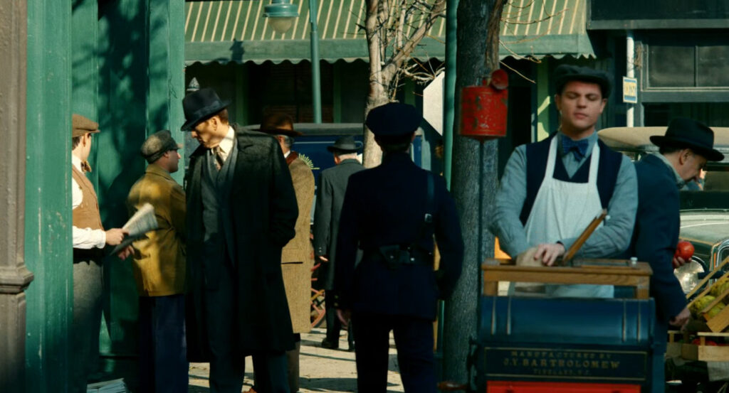Ben walking past a peanut vendor on the sidewalk.