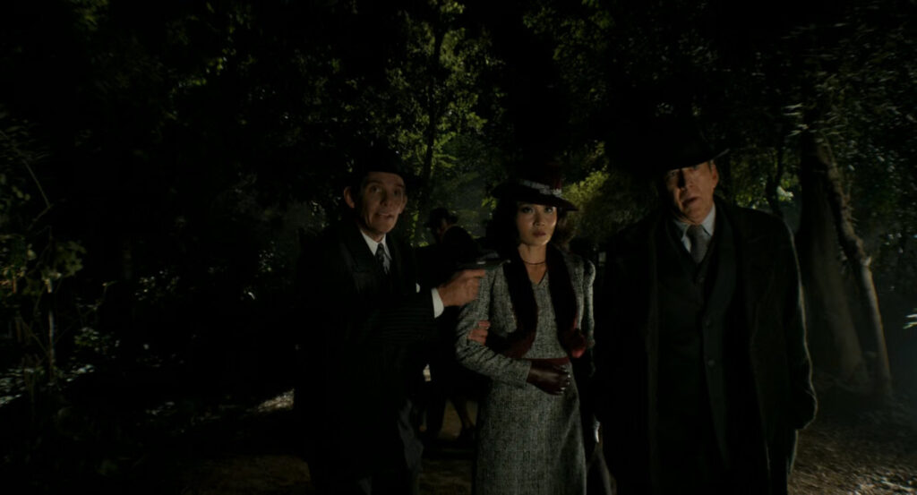 Winston holding Cat and Ben at gunpoint in the woods.
