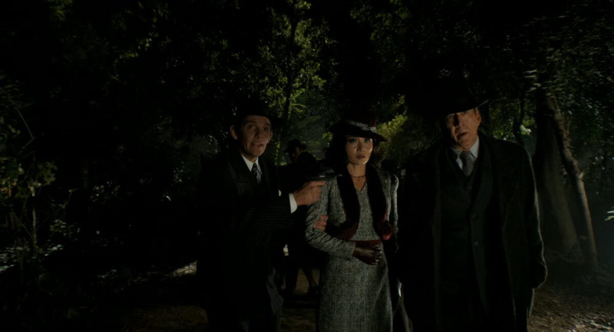 Winston holding Cat and Ben at gunpoint in the woods.