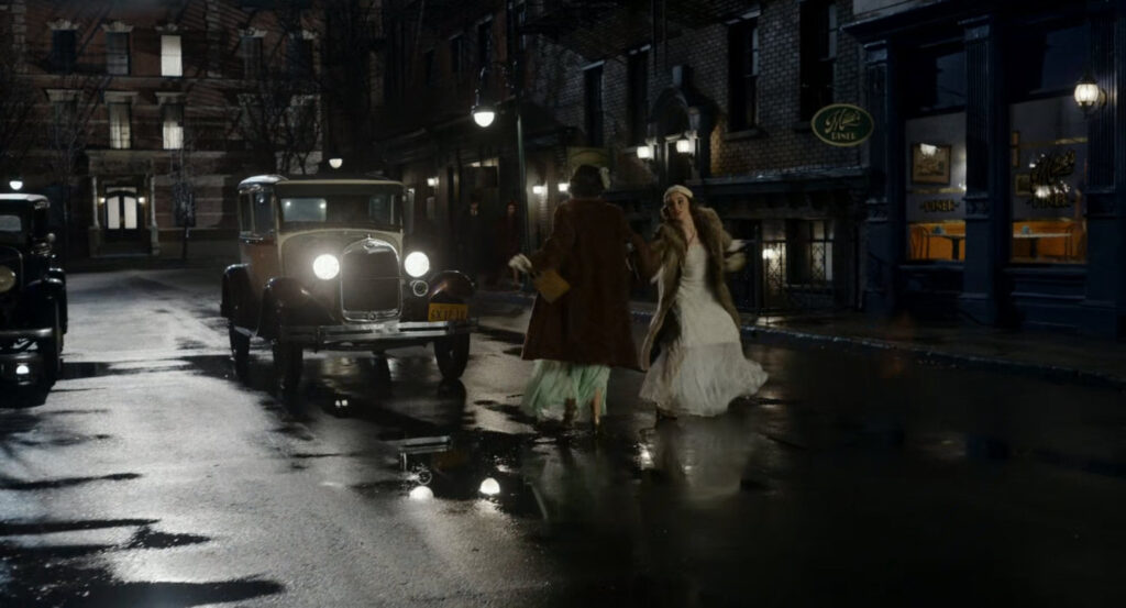 Two women avoid a car in the street outside Millie's Diner.