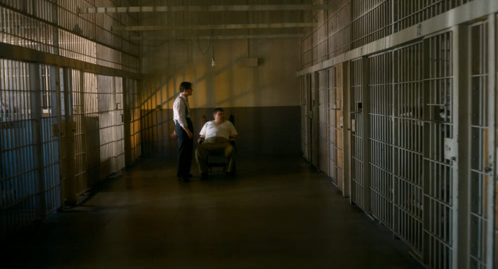 Detective interrogates Leyden in police station.