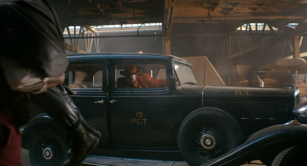 Robbie in a stolen police car in a warehouse in Harlem.