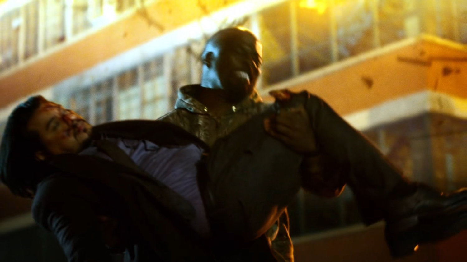 Luke carrying Colon outside Diamondback's exploding arms warehouse.