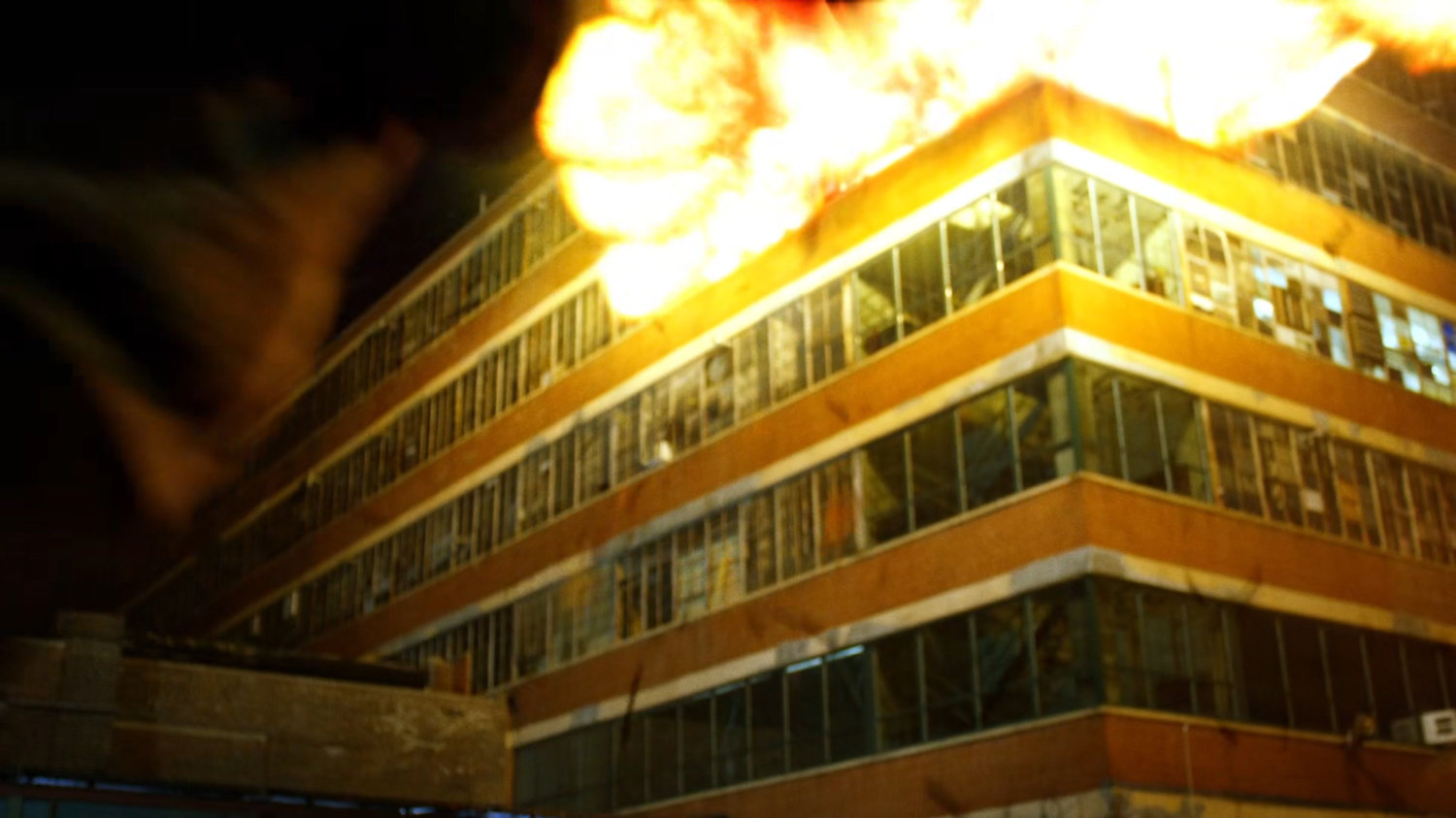 Luke carrying Colon outside Diamondback's exploding arms warehouse.