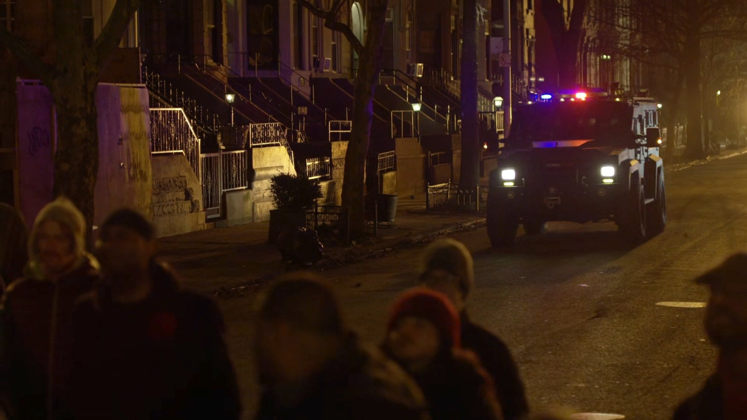 A police vehicle approaches a crowd on a Harlem street.