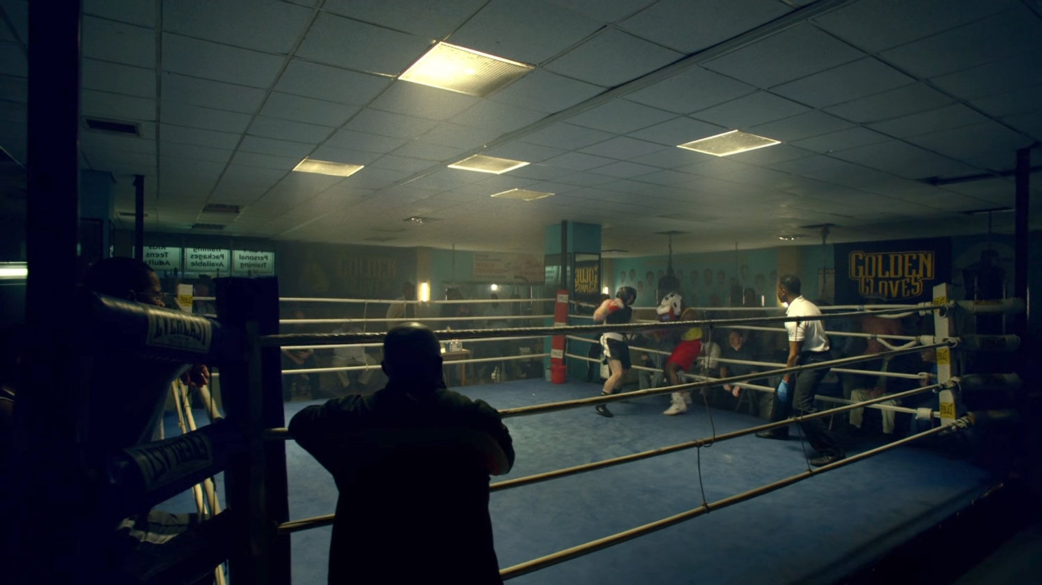 Young Carl and another teenager sparring in a boxing gym.